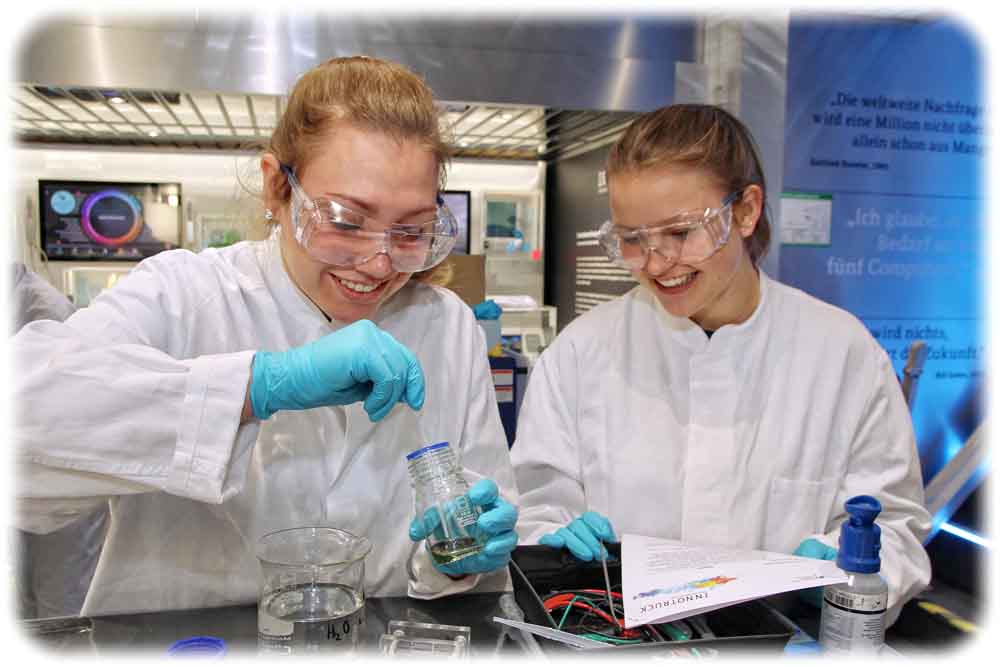 Zwei Schülerinnen füllen im Innotruck ein Elektrolyt in eine Redox-Flow-Batterie. Solche Fluss-Batterien eignen sich besonders als sehr große stationäre Stromspeicher. Foto: Flad & Flad für das BMBF