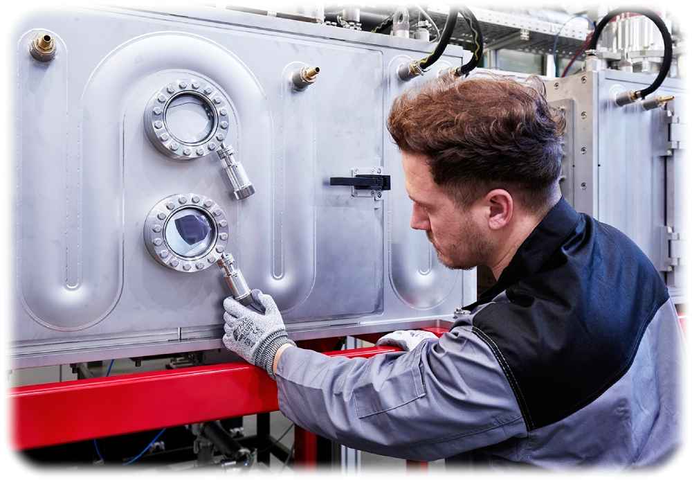 Ein Fraunhofer-Mitarbeiter prüft die Vakuumkammern an der Pilotanlage, die Bipolarplatten für Brennstoffzellen im Endlosbetrieb herstellen kann. Foto: Fraunhofer-IWS