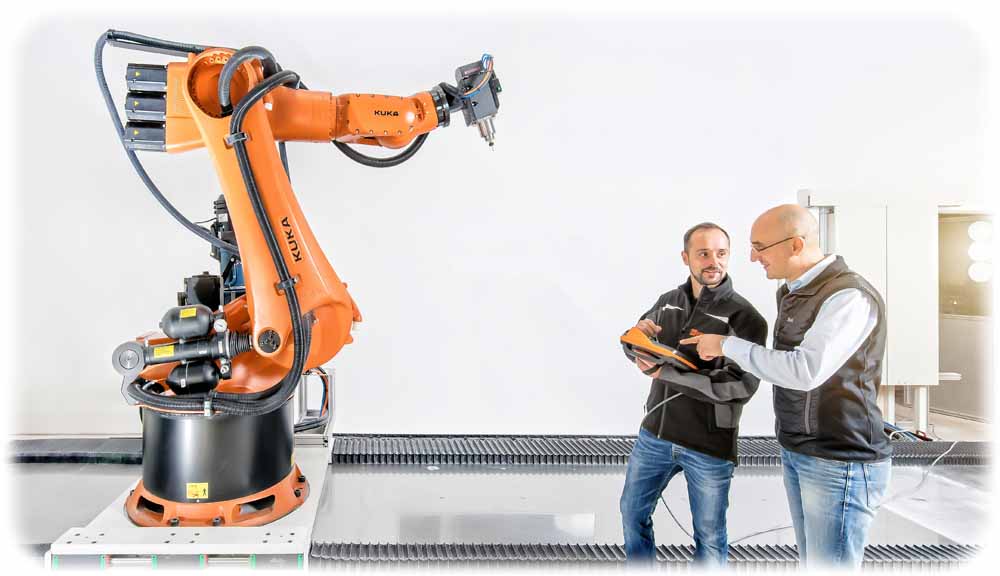 Entwickler Tobias Kastner (links) und  Geschäftsführer Sammy Techritz begutachten im Korropol-Labor den Kuka-Industrieroboter, der als Herzstück für den Riesen-3D-Drucker dienen soll. Foto: Korropol