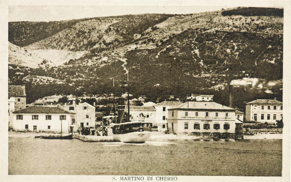Vista dal lato opposto della baia al mini-porto di Martinšćica nel 1928. Nella metà destra dell'immagine l'edificio più grande proprio sull'acqua è la distilleria Linardi.  Foto: cartolina storica