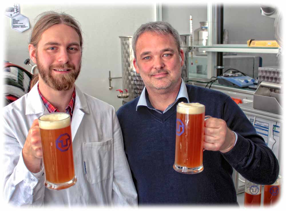 Stephen Schulz ist wissenschaftlicher Mitarbeiter von Prof. Jan Weigand. Hier stoßen beide mit einem Alt an, das sie in ihrer Uni-Brauerei zubereitet haben. Foto: Heiko Weckbrodt