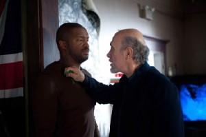 Liber8-Guru Kagame (Tony Amendola, r.) zeigt Travis, wo der Hammer hängt. Foto: Universum-Film