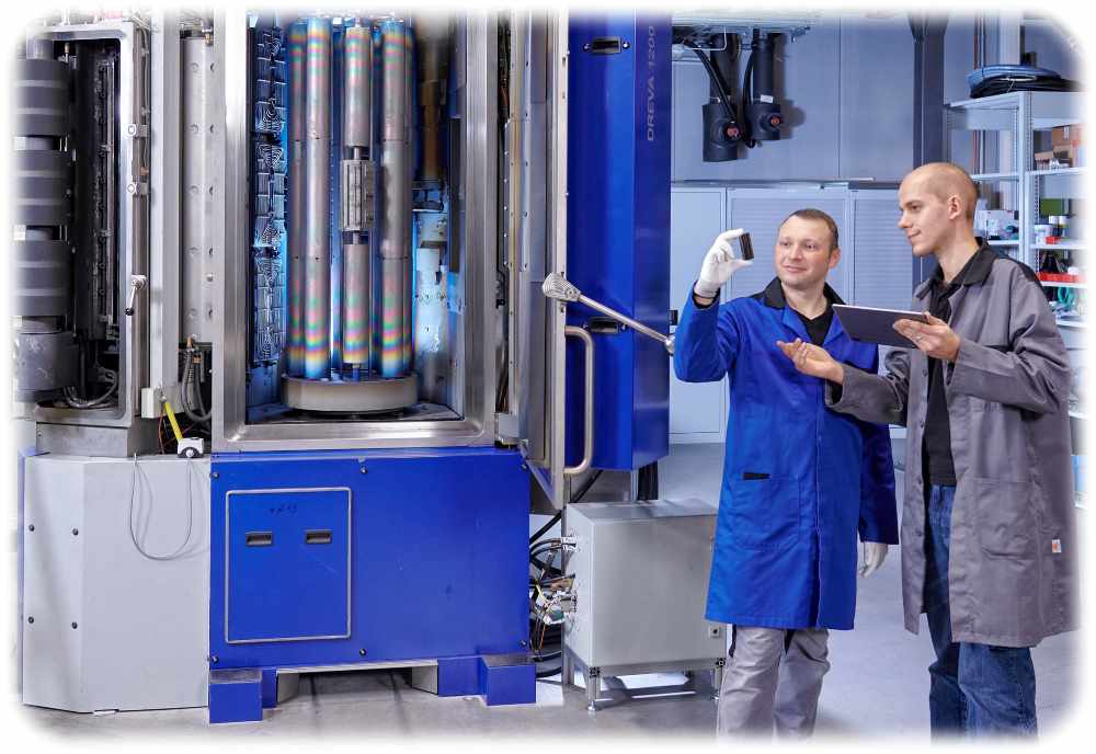 Zwei Experten stehen vor einer Laserbogen-Anlage mit einer Kohlenstoff-Quelle (ganz links im Bild) und begutachten kohlenstoff-beschichtete Bauteile. Foto: Jürgen Jeibmann für das Fraunhofer IWS Dresden