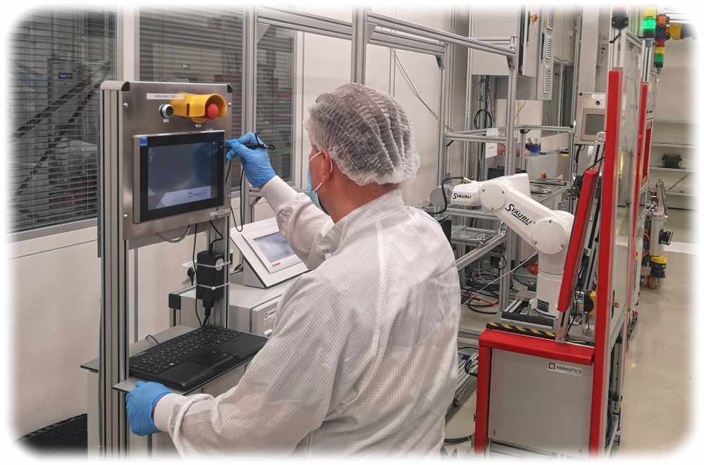 Ein Mitarbeiter kontrolliert in der Fabmatics-Fabrik in Dresden einen schienengebundenen Roboter, der künftig in einer Chipfabrik die Anlagen mit Wafer-Boxen bestücken soll. Foto: Heiko Weckbrodt