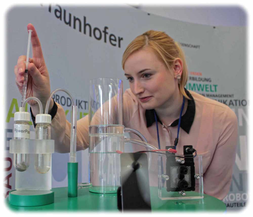 Julia Scholz vom IFAM füllt eine Prise Energiepaste in eine Demonstrations-Anlage. Gemischt mit Wasser, entsteht reiner Wasserstoff, der in einer Brennstoffzelle zu Strom verbrannt wird und hier im Beispiel einen Ventilator antreibt. Foto: Heiko Weckbrodt