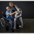 Eine Frau hebt einen Senior mit einem Apogee-Exoskelett aus einem Rollstuhl. Foto: German Bionic