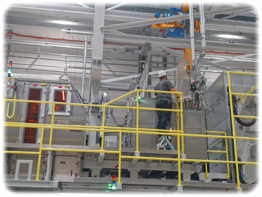 Ein Arbeiter hängt in die neue Helitek-Verkapselungsmaschine eine Folie für die Produktion organischer Solarzellen ein. Foto: Heiko Weckbrodt