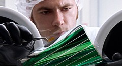 Ein Heliatek-Mitarbeiter prüft ein biegsames Organiksolar-Panel aus der Laborfertiguung. Abb.: Heliatek