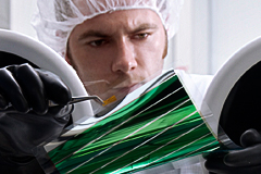 Ein Heliatek-Mitarbeiter prüft ein biegsames Organiksolar-Panel aus der Laborfertiguung. Abb.: Heliatek