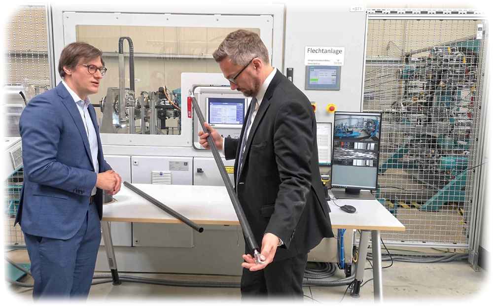 Herone-Chef Daniel Barfuß (links) zeigt dem sächsischen Wirtschaftsminister Martin Dulig seine Carbonband-Flechtmaschine (Hintergrund) und eines der Leichtbauteile. Foto: Heiko Weckbrodt