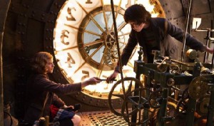 Hugo und Isabelle justieren das Schlagwerk der großen Bahnhofsuhr - die Zahnräder, Federn und anderen Mechaniken machen viel von der Faszination des Films aus. Abb.: Paramount