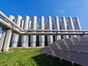 Eine Photovoltaik-Anlage in Ost-West-Ausrichtung und dahinter Warmwasserspeicher im Innovationskraftwerk Dresden-Reick. Foto: Heiko Weckbrodt