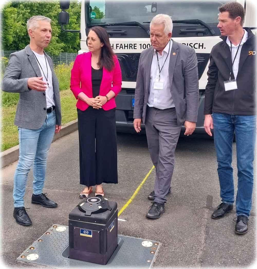 Projektleiter Matthias Breitkopf (links) vom Fraunhofer-Verkehrsinstitut IVI erklärt das Megaladen, bei dem der Elektrolaster nur über der versenkbare Säule parken muss. Rechts daneben IVI-Leiterin Sanaz Mostaghi, Alf Schwaten von der Stadtreinigung Dresden und sein Abfuhr-Abteilungsleiter Sven Gotscha. Foto: Heiko Weckbrodt