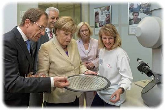 Bundeskanzlerin Angela Merkel mustert einen Wafer im Dresdner Infineon-Labor und lässt sich von Infineon-Konzernchef Reinhard Ploss (l.) die Technik dahinter erklären. Foto: Infineon