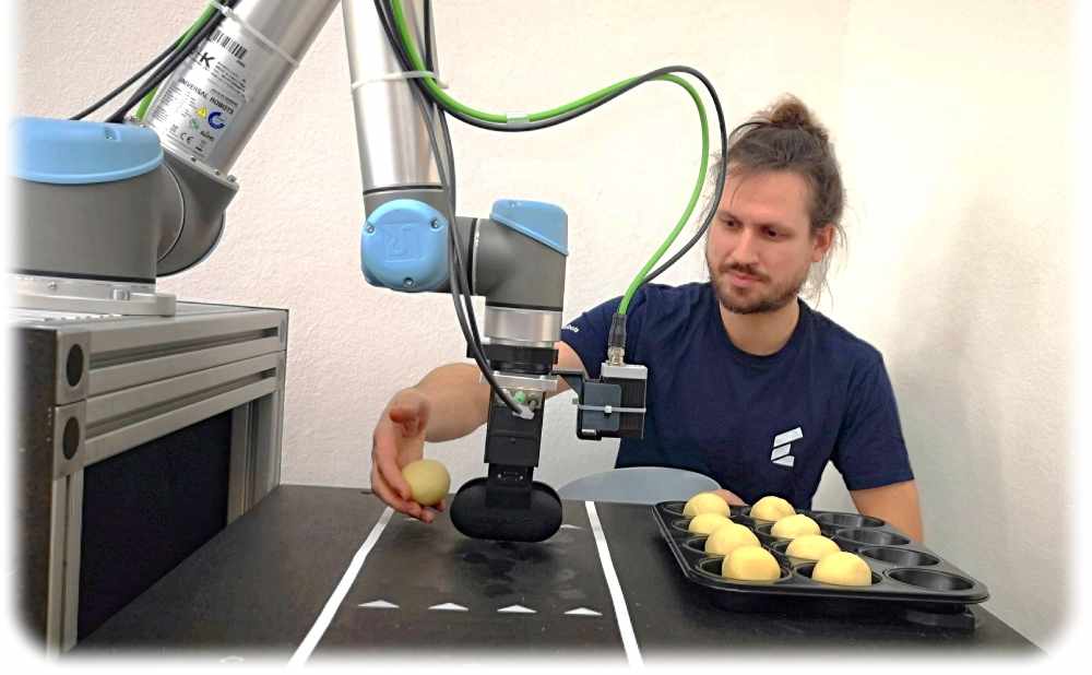 Timon Hitz von Wandelbots lernt im IoT-Labor vom Smart Systems Hub einen Roboter an, Teiglinge auf ein Blech zu sortieren. Foto: Heiko Weckbrodt