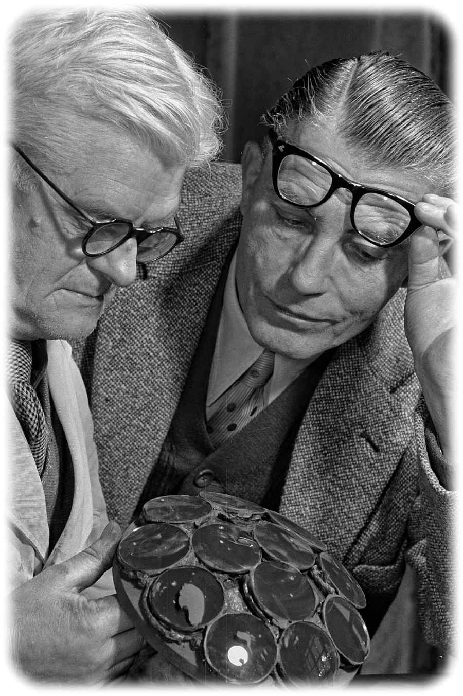 Karl Pouva (rechts) begutachtet 1951 mit einem Mitarbeiter auf einen Tragkörper gekittete Linsen für den Bildwerfer "Pouva Magica". Foto: Richard Peter jun., Deutsche Fotothek, Wikipedia, CC4-Lizenz, https://creativecommons.org/licenses/by-sa/4.0/