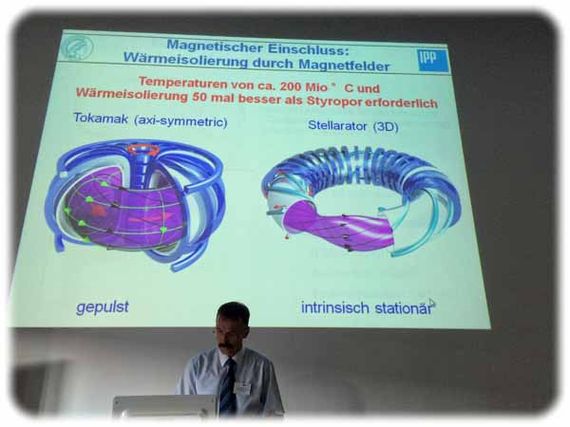 In der Grafik, die Prof. Robert Wolf hier zeigt, ist zu sehen, wie das Plasma-Magnetfeld beim ITER (links) geformt ist und welch bizarre Form es bei Stellarator-Kernfusionsreaktoren wie beim Wendelstein aussieht. Foto: Heiko Weckbrodt
