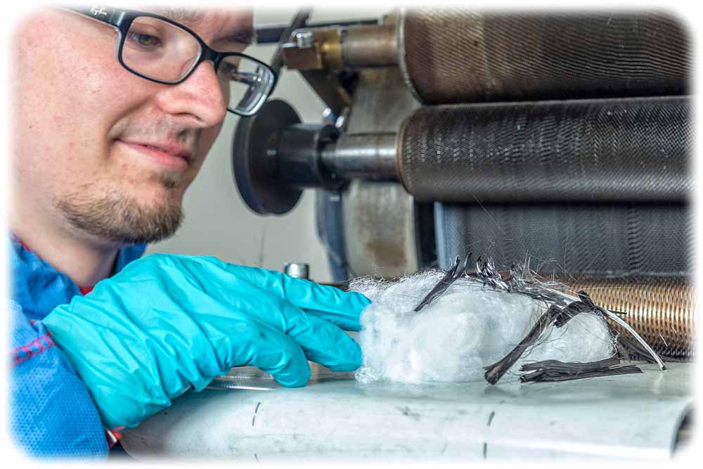 Martin Hengstermann, wissenschaftlicher Mitarbeiter und Doktorand am ITM der TU Dresden, an der Spezialkrempelanlage, mit der alte Karbonfasern wiederverwertet werden können. Foto: TUD/ITM