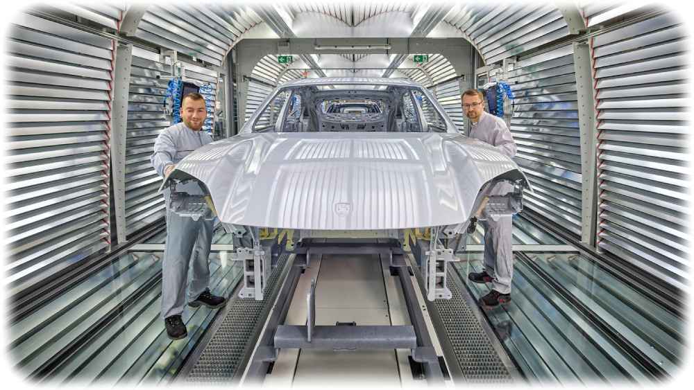 Zwei Mitarbeiter begutachten eine Karosserie im Lichttunnel der Lackiererei im Porsche-Werk Leipzig. Foto: Porsche