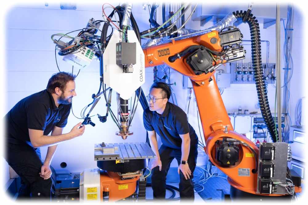 Zwei IWS-Mitarbeiter mustern einen Roboterarm mit einem Laserkopf. Foto: ronaldbonss.com für das Fraunhofer-IWS