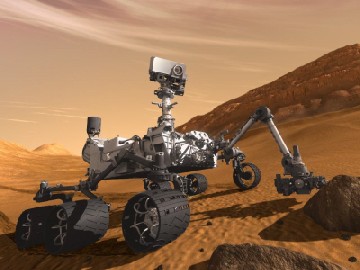 Die Visualisierung zeigt den neuen Mars-Rover "Curiosity" (Neugier), wie er mit seinem Roboterarm einen Mars-Brocken untersucht. Abb.: NASA