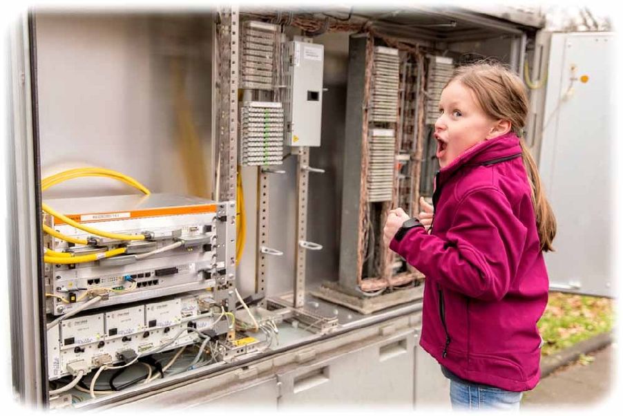Das Mädchen freut sich total über die neuen schönen Glasfasern im Schaltkasten, mit denen sie bald ganz schnell surfen kann. Foto: Deutsche Telekom