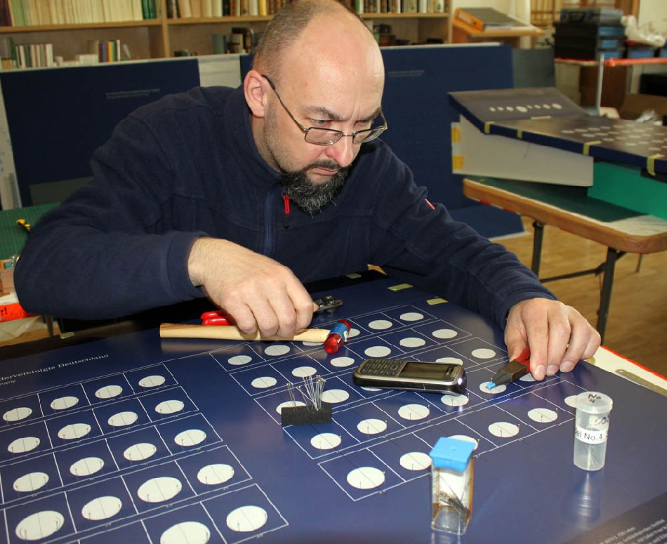 Voll konzentriert bereitet Matthias Voigt-Harraschta in der Werkstatt des münzkabinetts die objektträger für die Aufnahme der Münzen und Medaillen vor. Foto: Peter Weckbrodt