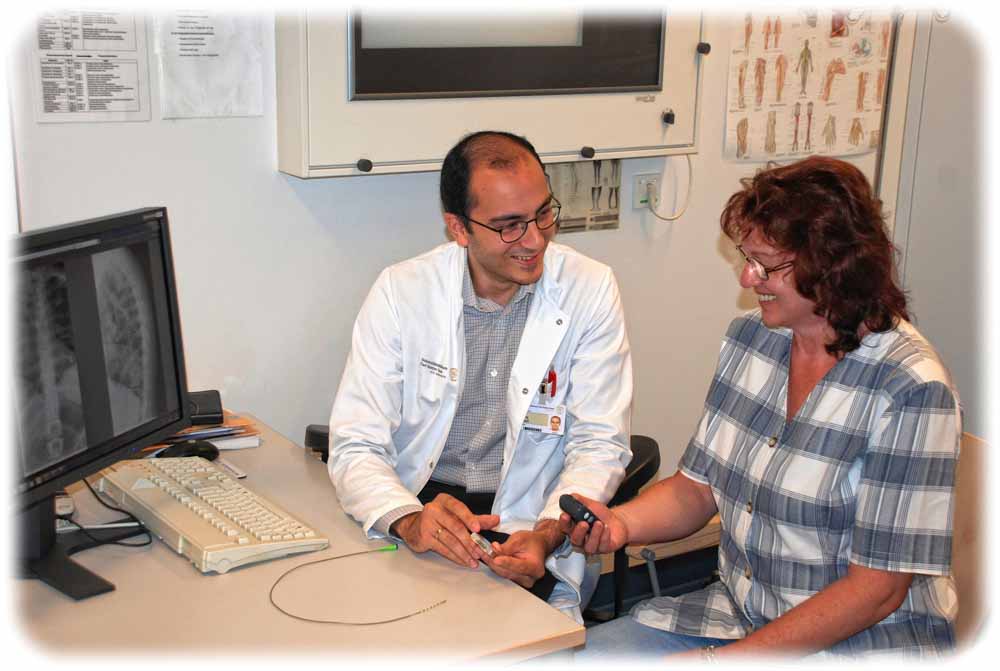 Neurochirurg Dr. Tareq Juratli zeigt seiner Patientin Sylvia Hesse ein Modell der implantierten Batterie. Foto: Uniklinik Dresden