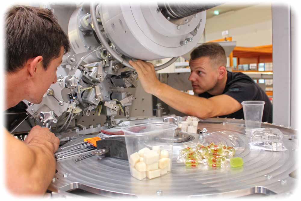 Die Mechatroniker Tom Gerstäcker (inks) und Philipp Pulina richten hier gerade eine Geleebonbon-Verpackungsmaschine ein, die für den export bestimmt ist. Foto: Heiko Weckbrodt