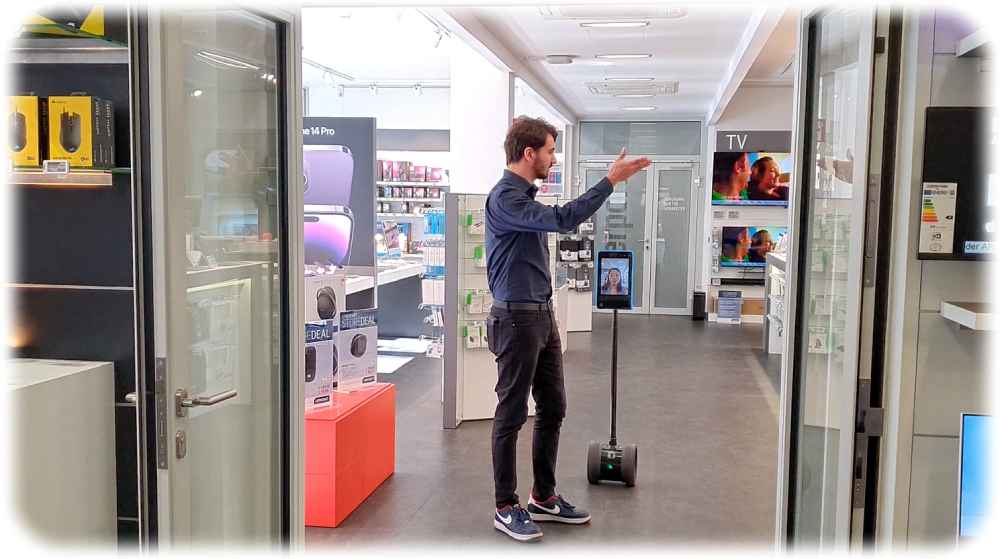 Ein Cyberport-Mitarbeiter zeigt in der Cyberport-Zentrale in Dresden, wie er nun Kunden beraten kann, die in einen Roboter als Avatar geschlüpft sind. Foto: Cyberport