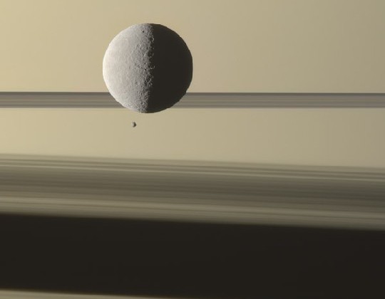 Der Mini-Mond Epimetheus (kleiner dunkler Punkt) schleicht sich über den Saturn-Ringen an die Titanin Rhea heran. Foto: G. Ugarković, ESA