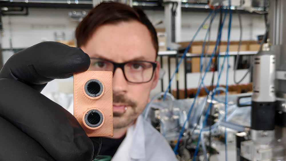 Johannes Rudolph prüft einen im 3D-Multimaterialdruck gefertigten Wärmetauscher. Foto: Fabian Lorenz für die TU Chemnitz