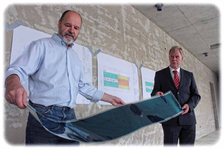 Dr. Hartmut Fröb (links) und Finanzminister Georg Unland entrollen schon mal eine der Solarfolien aus der Dresdner Helaitek-Fabrik, mit denen die Südfassade am Institutsneubau gepflastert werden sollen. Foto: Heiko Weckbrodt