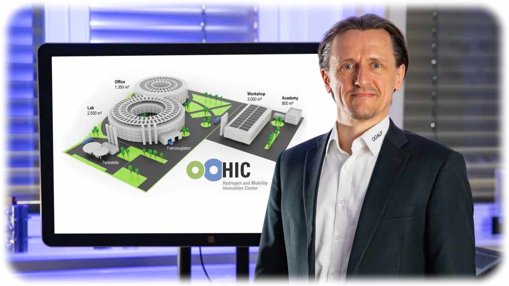 Prof. Thomas von Unwerth von der TU Chemnitz mit einer Visualisierung des entstehenden Wasserstoffzentrums im Hintergrund. Foto: Jacob Müller für die TUC