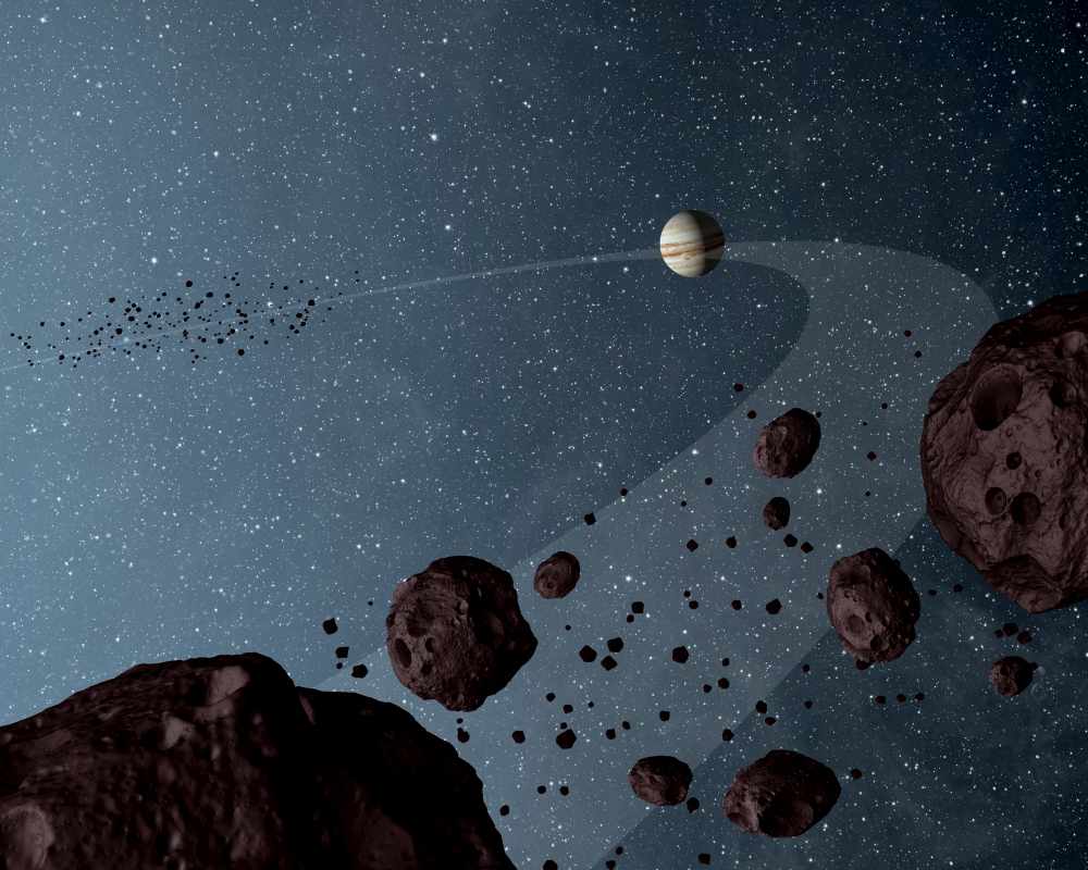Ein Hauch von Burgunderrot: Die künstlerische Darstellung zeigt, wie Trojaner-Asteroiden in einem Lagrange-Punkt des Jupiters (die helle Kugel hinten) die Sonne umkreisen. Illustration: NASA/JPL-Caltech