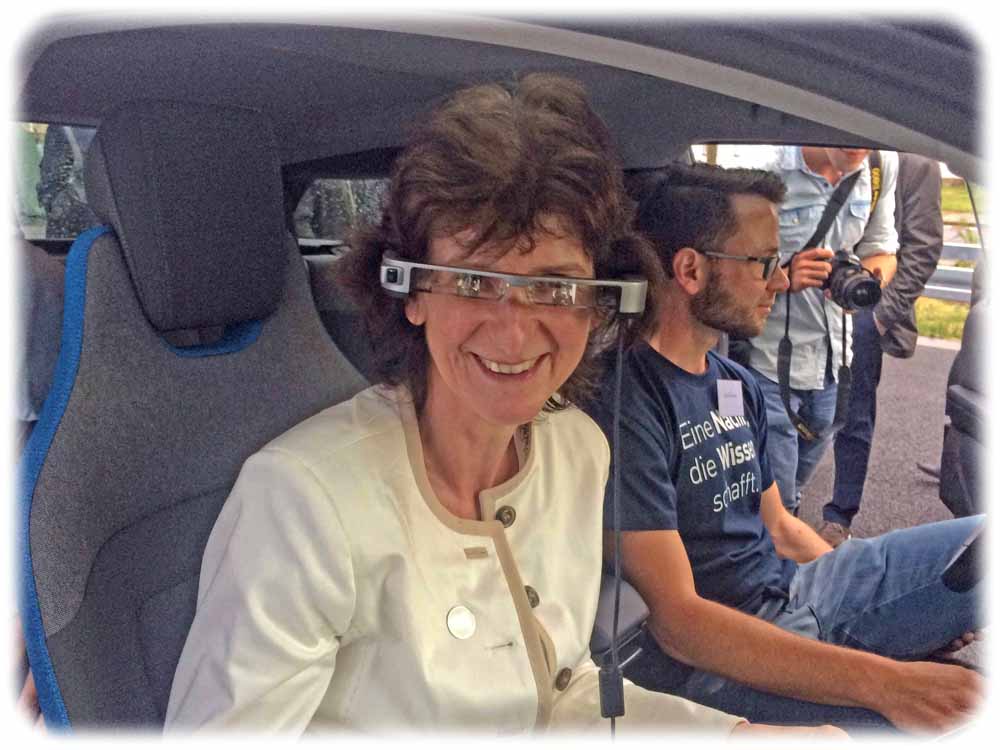 Die sächsische Wissenschaftsministerin Eva-Maria Stange hat in der HTW Dresden eine Datenbrille aufgesetzt, um die erweiterte Realität in einem von den HTW-Ingenieuren aufgerüsteten BMW i3 zu genießen. Zusätzlich zur realen Umgebung sieht man mit solchen "Augmented Reality"-Lösungen (AR) Gefahrenstellen voraus - selbst Unfallgefahren, die noch unsichtbar hinter der nächsten Ecke lauern. Foto: Heiko Weckbrodt