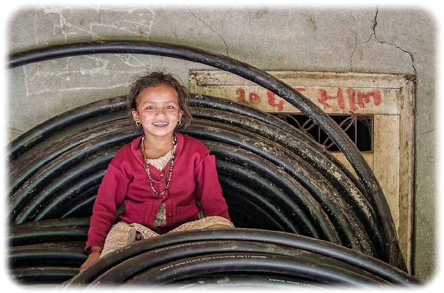 Nepal: Ein nepalesischen Mädchen sitzt in Gyhanphedi auf den Leitungen, die arche noVa in die abgelegenen Bergdörfer gebracht hat. Foto: arche noVa