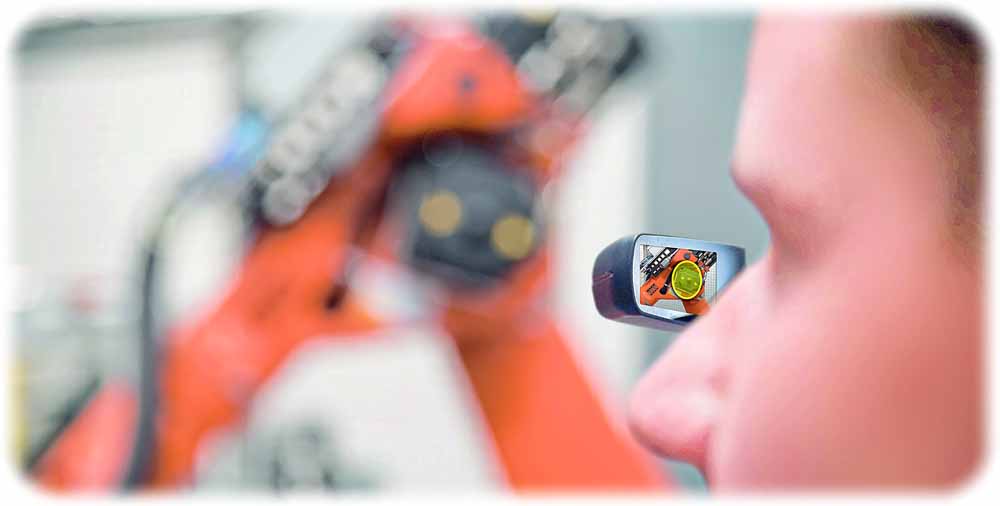 Ein Bosch-Mitarbeiter mustert mit einer "Augmented Reality"-Brille einen Roboter. Solche AR-Datenbrillen zeigen dem Träger deren reale Umgebung und andererseits per Computer eingespiegelte Zusatzinformationen wie beispielsweise Reparaturanleitungen. Per 5G-Mobilfunk können Mensch und Computer mit solchen Systemen ohne spürbare Verzögerungen kommunizieren. Foto: Bosch