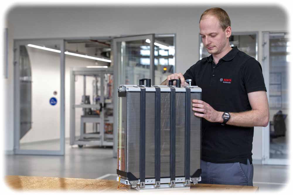 Ein Bosch-Mitarbeiter kontrolliert einen Stapel aus Reaktionsplatten. Solche "Stacks" sind die Herzstücken von Brennstoffzellen. Foto: Bosch